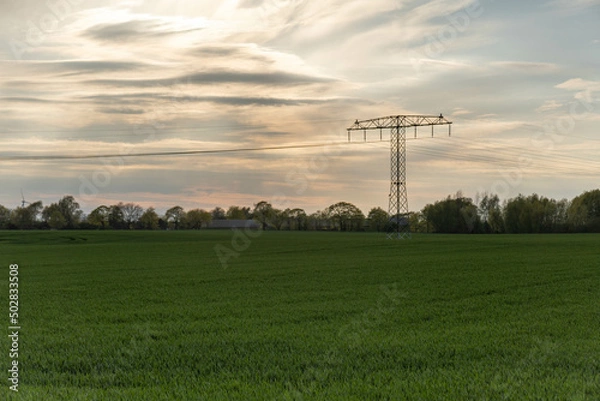 Fototapeta sunset sky over a green field with power pole