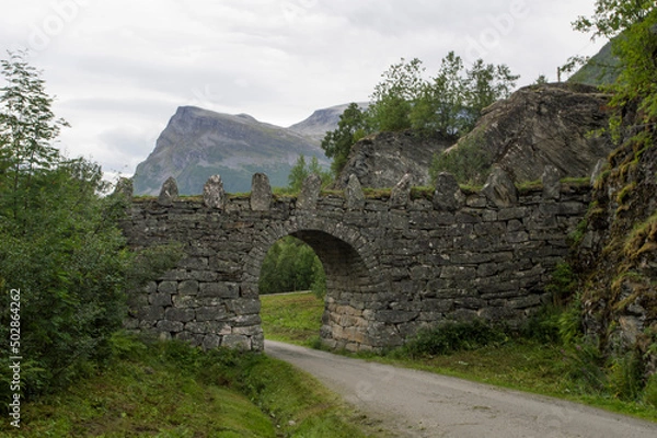 Fototapeta old stone bridge in Norway, near Geiranger. Misty mountains and cloudy sky on the background