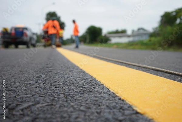 Fototapeta Blurred image of yellow traffic marking work on paved road