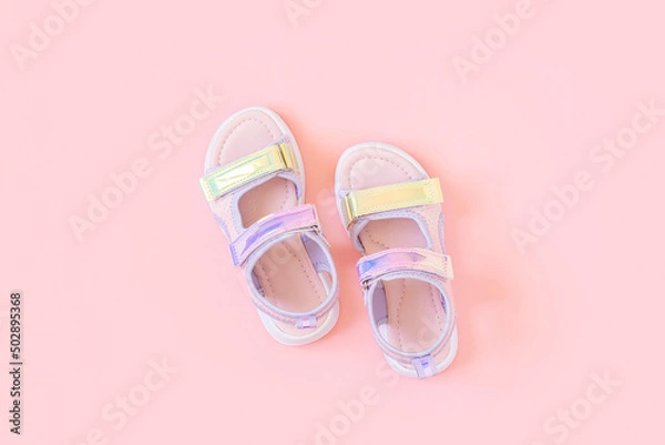 Obraz Stylish holographic sandals for kids on pink background. Shiny fashion summer shoes. Flat lay, Top view