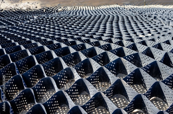 Obraz Geogrid on the slope of the road, road construction. Laying a geogrid so that the slope is not washed away by water.