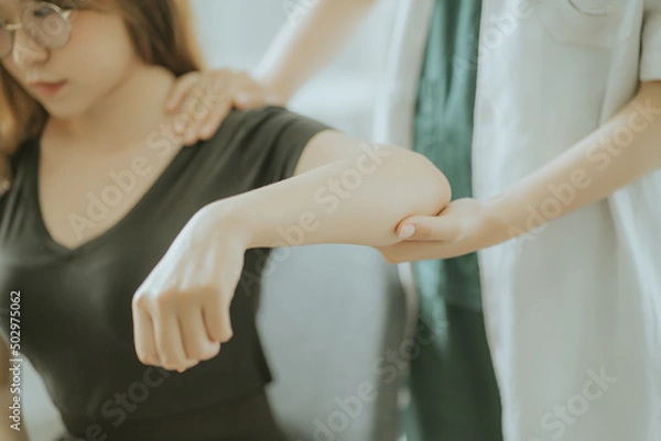 Fototapeta Physiotherapist is doing physical therapy for a patient, the patient has body aches due to overwork and has undergone treatment and physiotherapy with a professional physiotherapist.