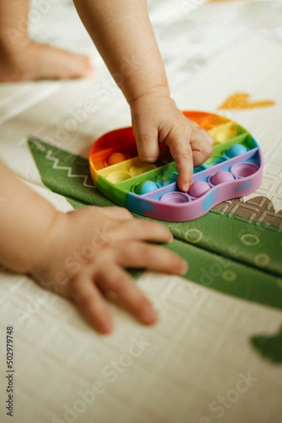 Obraz Child's hands touching a round rainbow Pop It