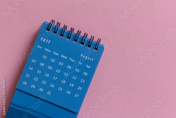 Fototapeta Desktop mini calendar for August 2022 on a pink background.