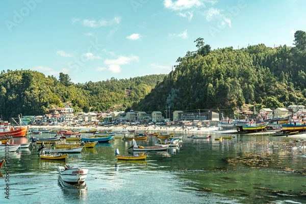 Fototapeta Wide colorful horizontal shot of boats and ships during sunset in Caleta Tumbes with village and mountains in the background, Chile