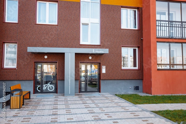 Fototapeta Entrance of a new modern residential apartment building with parking for bicycles and a bench. Concept of modern apartments