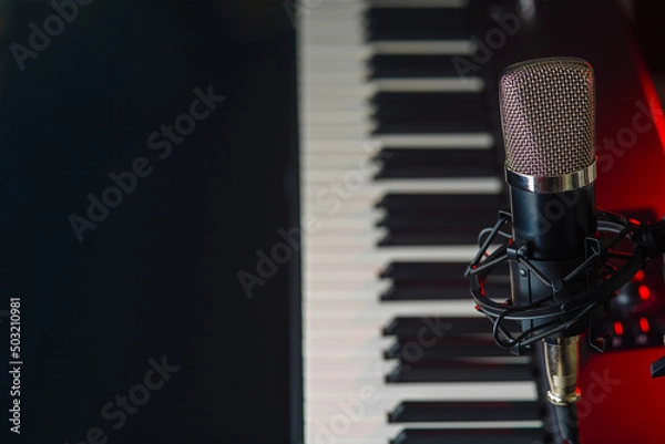 Fototapeta Synthesizer, midi keyboard and microphone on a black background. Close-up. Recording studio, concerts, performances, rehearsals, workplace of a musician, singer, composer.