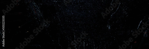 Fototapeta Dark creative background - rough linen canvas unevenly covered with black primer, reflections of light. Toning, blurring, selective focus.