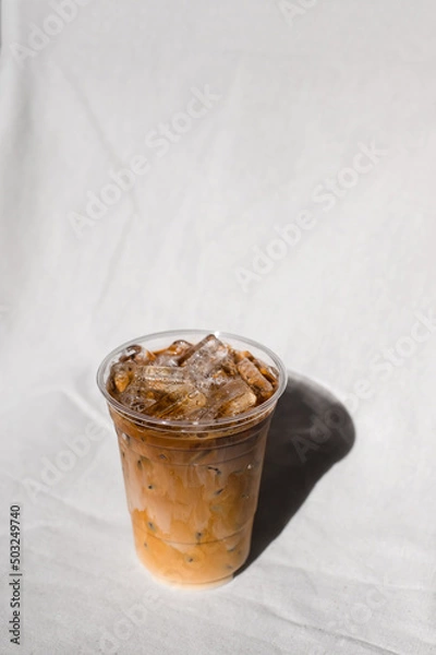 Fototapeta Close-up plastic glass of iced coffee with milk on the table