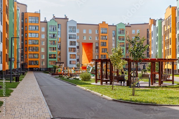 Fototapeta Bright urban landscape of a new residential area with modern multi-apartment colored houses and a well-maintained house territory