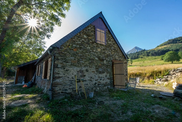 Fototapeta Authentic renovated Pyrenean barn in the Aure valley. slate roof, exposed stone and wood construction. amazing view on the mountains