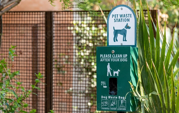 Fototapeta Pet waste station in park with plastic bags and instructions for use. Public dog feces disposal station.