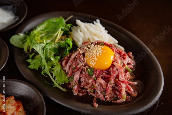 Obraz Korean Grilled BBQ combo sets with egg yolk beef tartare with pickle salad on the dark plate and black table vibe background, and pickle dishes