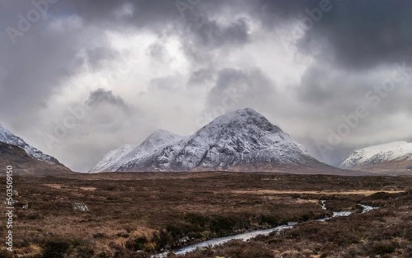 Fototapeta Beautiful Winter landscape image of Stob Dearg Buachaille Etive Mor viewed from Rannoch Moor with snowcapped peak and beautiful moody cloud formations