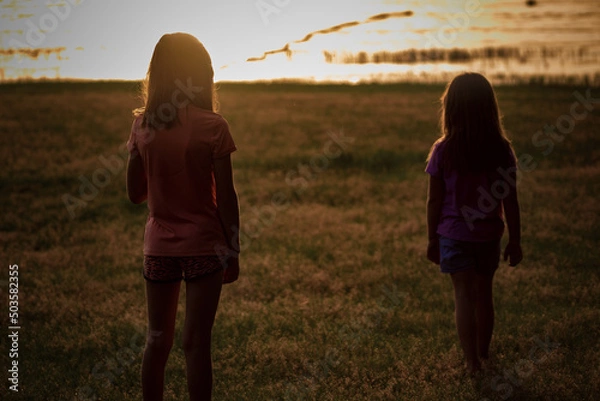 Fototapeta sisters on lake at sunset