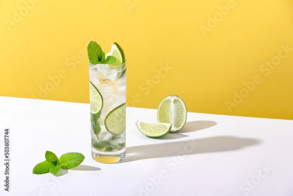 Fototapeta Ice and mojito in a glass lie on the table with a strong shadow