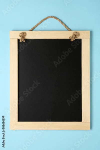 Fototapeta Clean small black chalkboard on light blue background, top view