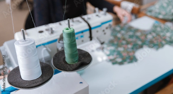 Fototapeta Close-up spool of multicolored threads for sewing machine. Concept Interior of garment factory