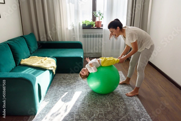 Obraz Mother do exercises playing with her baby at home.