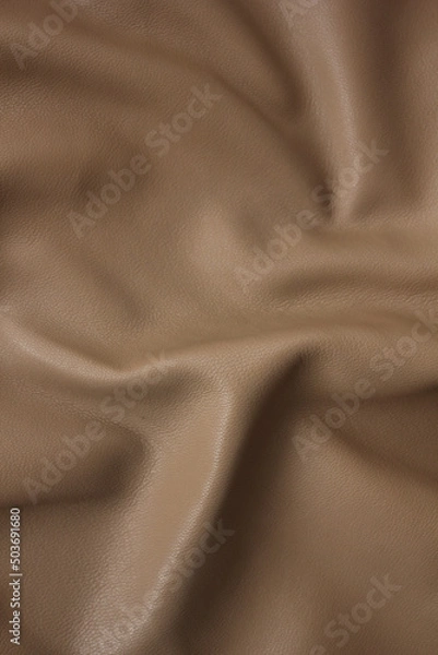 Fototapeta  a piece of caramel beige artificial leather close-up with Abstract waves and folds of fabric