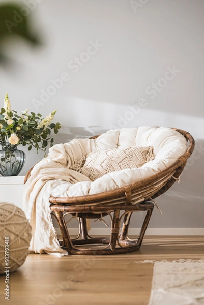 Fototapeta Rattan papasan chair with a beige pillow in a modern luminous apartment 