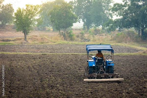 Fototapeta Indian farmer working with tractor in agriculture field