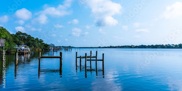Fototapeta Blue water view with private wooden piers on the Sebastian River in Little Hollywood, Mikko, Florida. Panoramic photo in blue tones