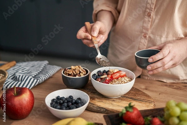 Obraz Woman adding seeds to bowl of muesli