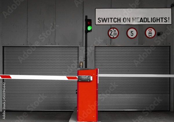 Fototapeta Subterranean parking garage entry gate with switch on headlights sign