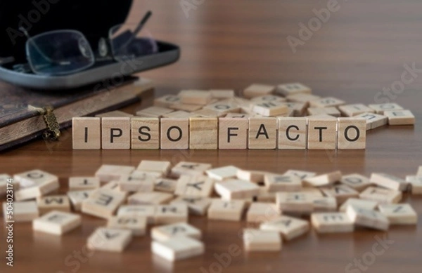Obraz ipso facto word or concept represented by wooden letter tiles on a wooden table with glasses and a book