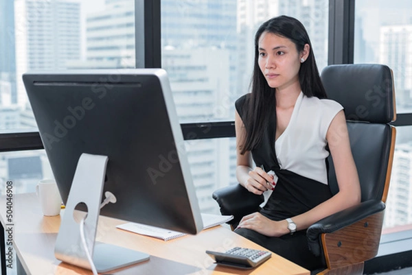 Fototapeta asian business woman stand and  look at computer for planning business , reading message or email on monitor