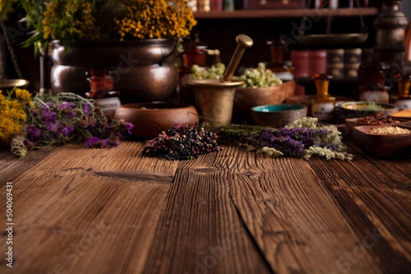 Fototapeta Natural medicine background. Assorted dry herbs in bowls and brass mortar on rustic wooden table.