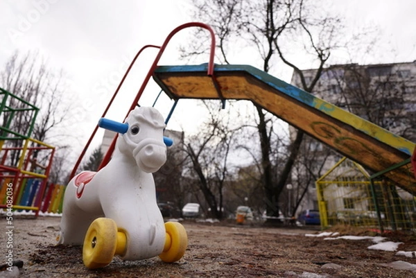 Fototapeta Empty playground in a residential area with colorful climbing frame and slide and white pony