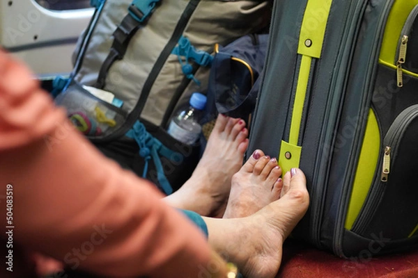 Obraz Women traveling on a train with their shoes on with luggage and feet with lacquered toenails on the seat