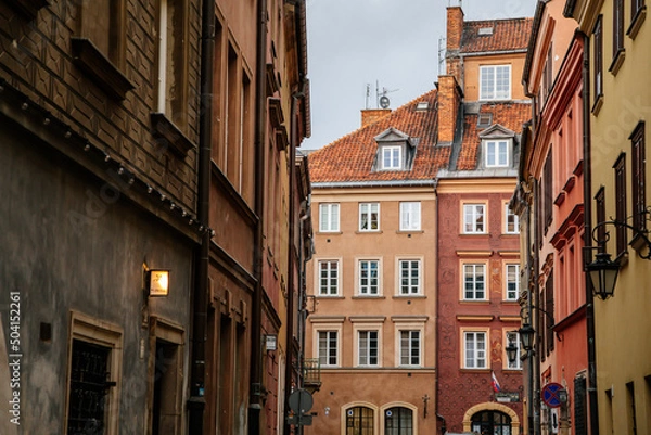 Fototapeta Warsaw, Poland, 13 October 2021: Narrow picturesque street with colorful buildings in historic center in medieval city, renaissance and baroque historical buildings at old town, sunny autumn day