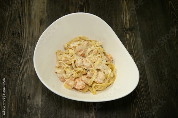 Obraz A white bowl with fettuccine alfredo noodles with shrimp.