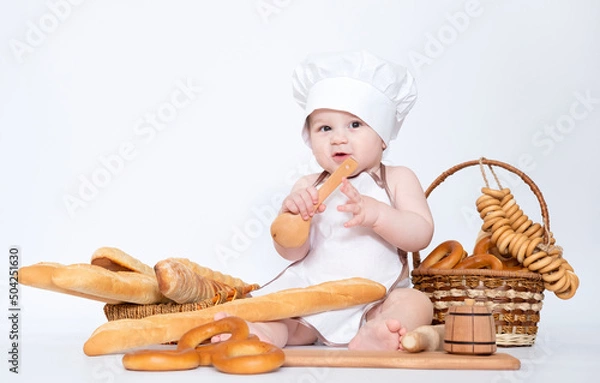 Fototapeta Little boy in a cook cap and with bread funny little chef