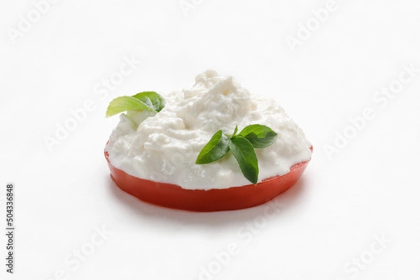 Fototapeta Stracciatella cheese on white background with basil on piece of tomato. Curd cheese product.