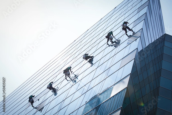 Fototapeta group of workers cleaning windows service on high rise building