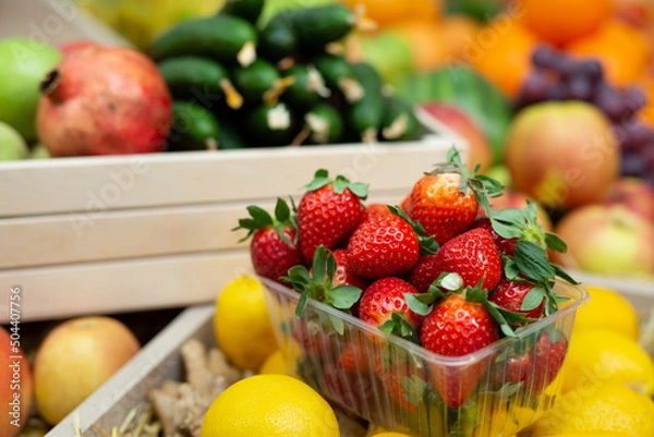 Fototapeta Tray of strawberries on the counter of a vegetable store among vegetables and fruits.