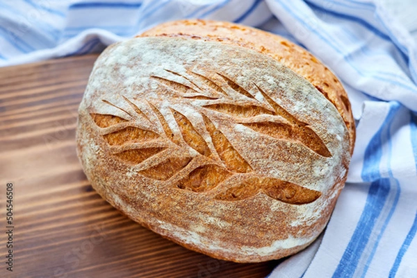 Obraz Freshly baked homemade wheat bread on a wooden background. Close-up, selective focus