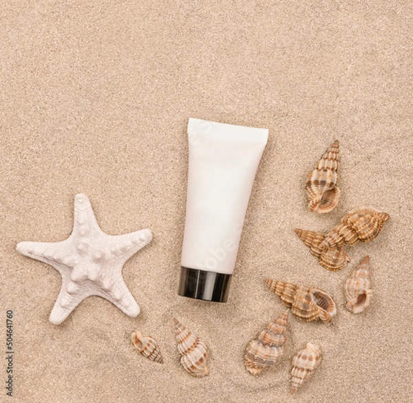 Fototapeta a suntan cream and seashells on sandy background