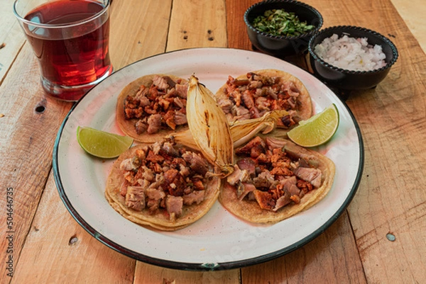 Obraz Tradicionales tacos mexicanos combinados servidos en una mesa con salsas y agua fresca de jamaica