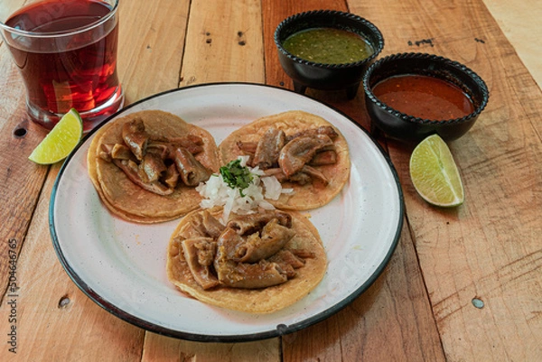 Obraz Tradicionales tacos mexicanos de tripa servidos en una mesa con salsas y agua fresca de jamaica 