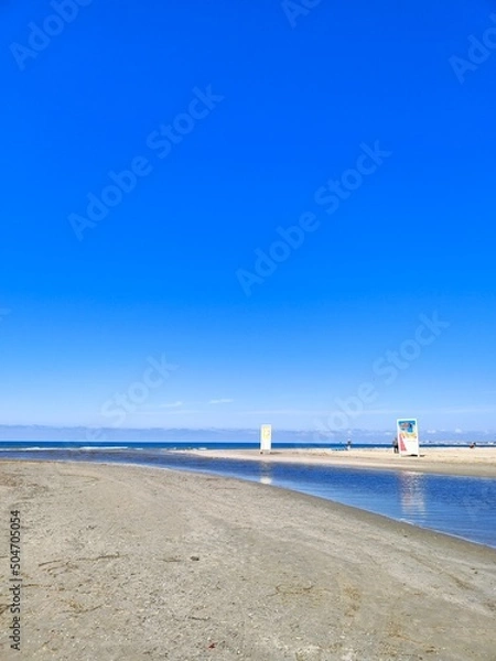 Fototapeta The Black Sea in spring with waves and sand on the beach with a bright blue sky.