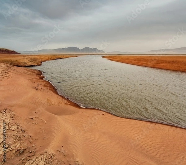 Obraz The shore of the Krasnoyarsk reservoir without water, sandy ripples, clay and hills, rainy sky over Mount Tepsey Tepsei