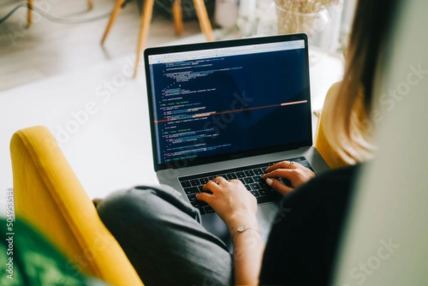 Fototapeta Young woman mobile developer writes program code on a computer, programmer work.