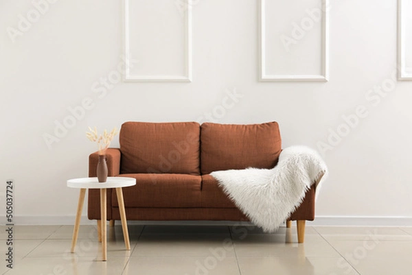 Fototapeta Soft sofa and table near light wall in living room