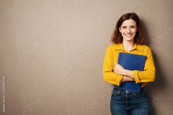 Obraz Laughing young woman against a brown background with her application documents in her hands
