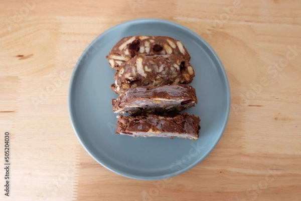 Fototapeta Homemade mosaic chocolate biscuit cake served in a blue plate, selective focus. It is called "Mozaik Pasta" in Turkish. That is texture of it not grain. Traditional Turkish dessert.